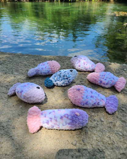 jouets poisson crochet multicolores posés près de l’eau, herbe à chat